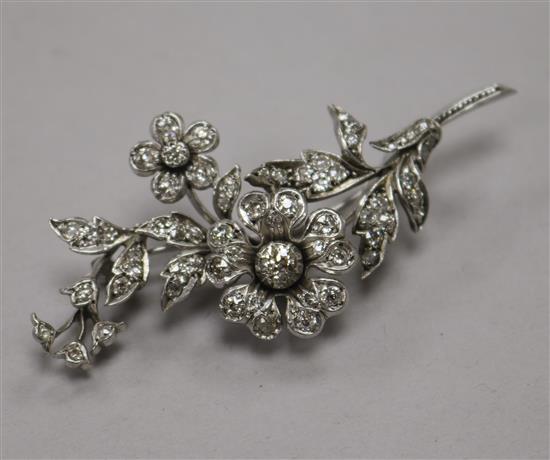 A white metal and diamond set floral spray brooch, size 7cm.